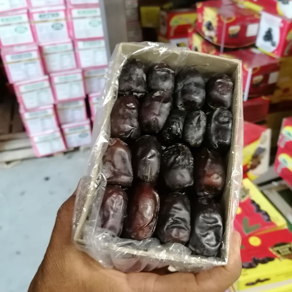 A tray of Mazafati dates held over stacked cartons